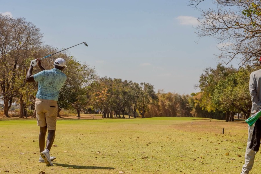 A golfer tees off down a wide, open fairway